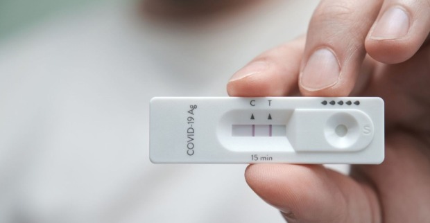Hand, die positiven Corona-Schnelltest hält