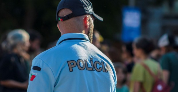 Polizist von hinten im Einsatz, er trägt eine blaue Uniform und eine dunkle Kappe