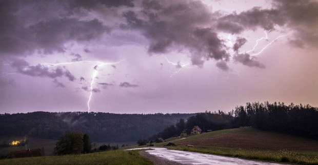 Unwetter in Österreich: dunkler Himmel mit Blitzeinschlag über einem Wald
