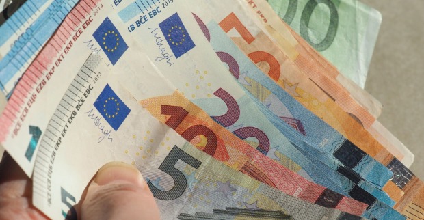 Hand hält aufgefächerte Euro-Banknoten in verschiedenen Stückelungen (5, 10, 20, 50, 100 Euro).