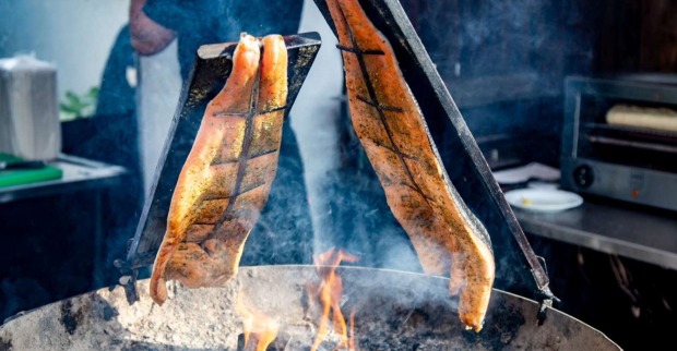 Zwei Stücke gewürzter Lachs werden traditionell als Flammlachs über offenem Feuer gegart.