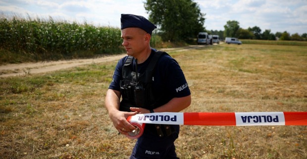 Polnischer Polizist mit Absperrband sichert ein Feld bei Osiny nach dem Absturz einer russischen Drohne.