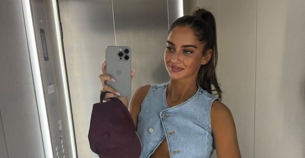 Tanja Makaric posiert in einem Aufzug und zeigt ihren Babybauch, in der Hand hält sie eine Kappe