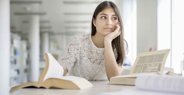 Nachdenkliches Mädchen sitzend vor einem Schreibtisch