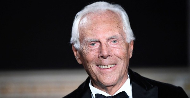Porträt von Giorgio Armani mit weißem Haar, der im Smoking und mit Fliege in die Kamera lächelt.
