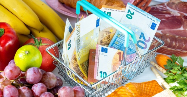 Einkaufskorb mit Euro-Banknoten zwischen Obst, Gemüse, Wurst und Käse – Symbolbild für steigende Lebensmittelpreise.