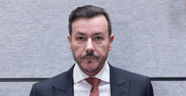 René Benko im Gerichtssaal in Innsbruck, Blick nach vorne, ernster Gesichtsausdruck, erster Prozesstag wegen Betrugsverdachts.