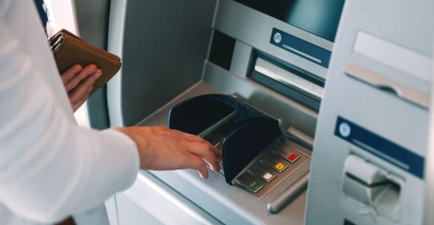 Frau an einem Bankomaten, die Geld beheben will