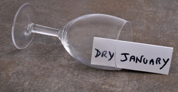 Leeres, umgestoßenes Weinglas, in dem auf einem Zettel Dry January geschrieben steht