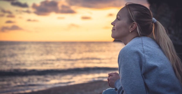 Frau am Strand bei Sonnenuntergang | Credit: iStock.com/splendens