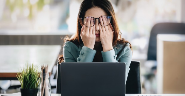 Frau hinter Notebook mit Händen vor ihren Augen | Credit: iStock.com/Jirapong Manustrong
