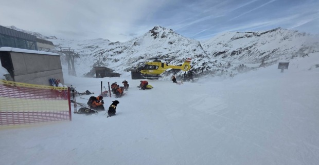 Bergretter und Lawinenhunde arbeiten im Schnee, während ein gelber Rettungshubschrauber in den Bergen von Bad Gastein landet.
