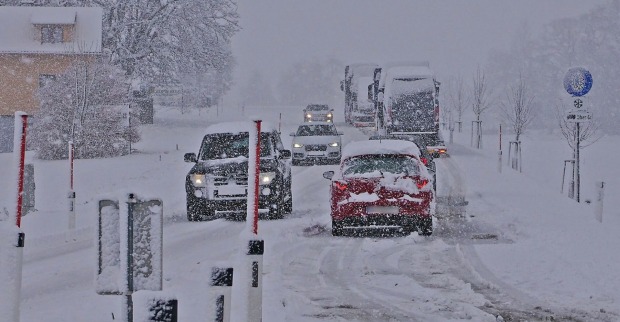 Autos auf einer verschneiten Fahrbahn.