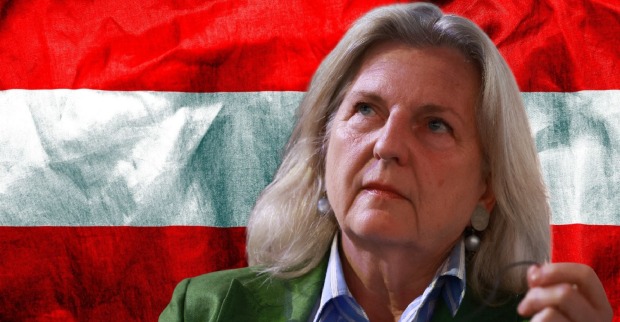 Karin Kneissl blickt nachdenklich bei einer Veranstaltung, sie steht wegen umstrittener Aussagen über Österreich in der Kritik, vor einer großen Österreich-Flagge