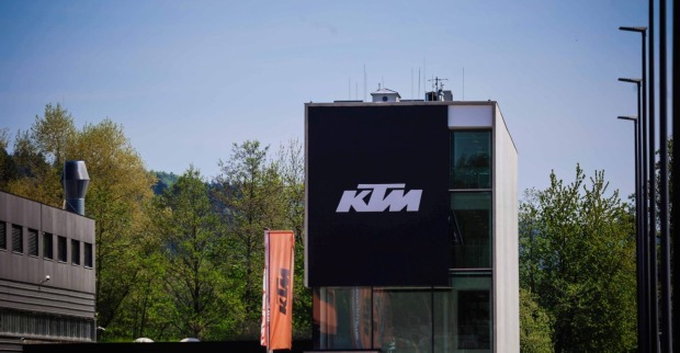 KTM-Firmengebäude in Mattighofen mit großem KTM-Logo an der Fassade und orangen Fahnen vor dem Gebäude.