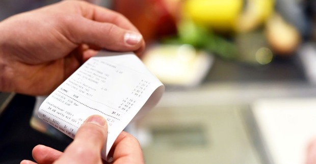 Mann hält nach einem Einkauf im Supermarkt eine Rechnung in seinen Händen