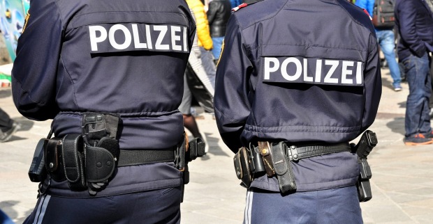 Zwei Polizisten in Uniform von hinten, im Einsatz auf einer Straße in Österreich, Themenbild für den Angriff auf zwei Tierärztinnen in Bad Wimsbach.
