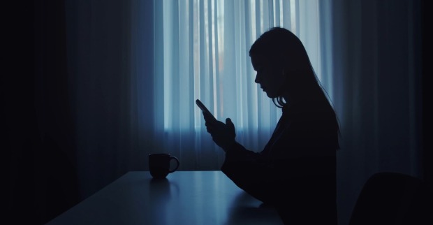 Frau im Dunkeln am Telefon/ Frau in Brandenburg blockiert Notruf durch Telefonterror