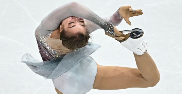 Eiskunstläuferin Olga Mikutina während ihrer Kür bei Olympia 2026 in Mailand, in einer schwierigen Pirouettenpose auf dem Eis.