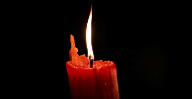 Rote Kerze mit Flamme im Dunkeln als Symbol für Trauer um Mel Schilling, „Married at First Sight“-Star, die mit 54 an Krebs gestorben ist