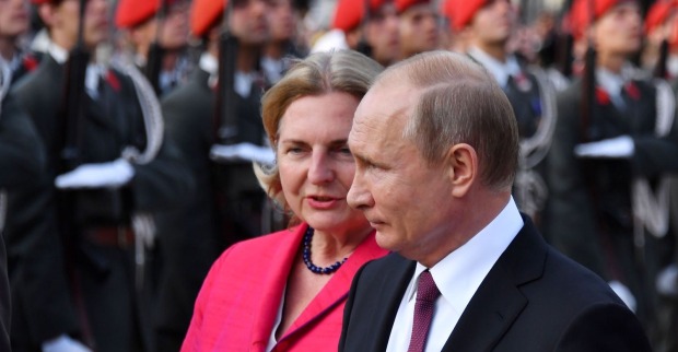 Karin Kneissl neben Wladimir Putin bei einem offiziellen Termin mit Militär im Hintergrund