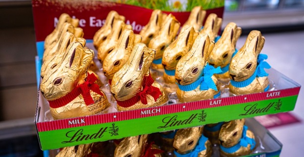Mehrere Lindt Goldhasen stehen dicht nebeneinander in einem Supermarktregal und zeigen die typische goldene Verpackung mit Schleife.