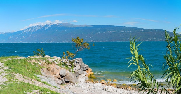 Gardasee mit klarem Wasser und Bergen im Hintergrund während seltener vollständiger Durchmischung des Sees