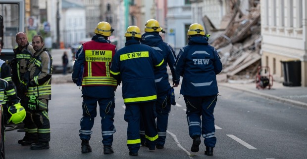 THW-Einsatzkräfte gehen durch eine Straße mit Trümmern eines eingestürzten Hauses in Görlitz, während Rettungsarbeiten laufen.