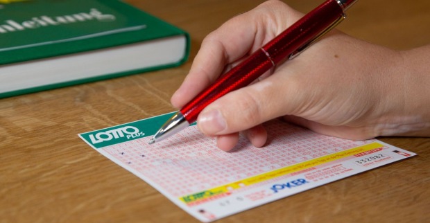 Hand die einen Schein der österreichischen Lotterien ausfüllt