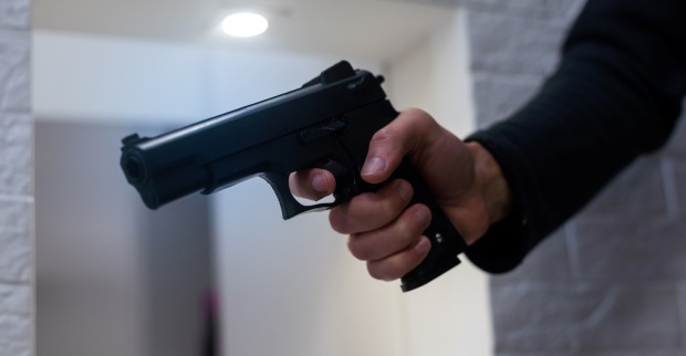 Bedrohung durch Feuerwaffen. Muzzle der Pistole in der Hand des Menschen wird auf die Kamera gezeigt.
