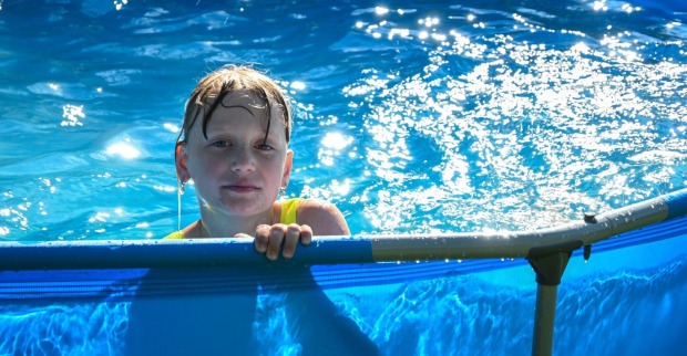 Ein Kind spielt in einem Aufstellpool bei Sonnenschein