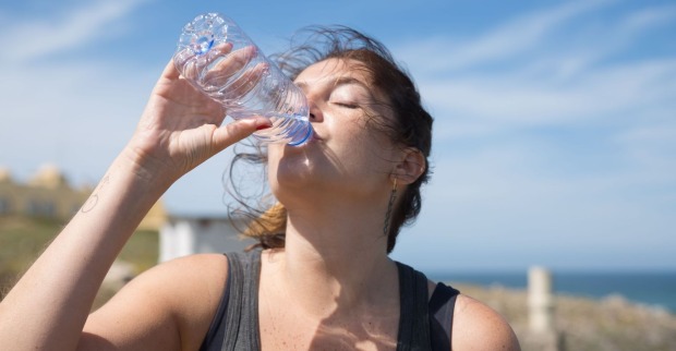 Frau trinkt Wasser während der Hitzewelle in Österreich, um sich bei extremer Hitze und Temperaturen bis zu 40 Grad abzukühlen.