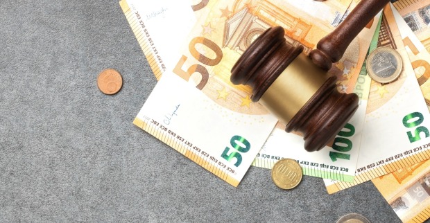 Hölzerner Richter, der auf grauem, strukturiertem Hintergrund Euro-Banknoten und -Münzen schuf, als Symbol für unerlaubtes Pflücken von Obst.