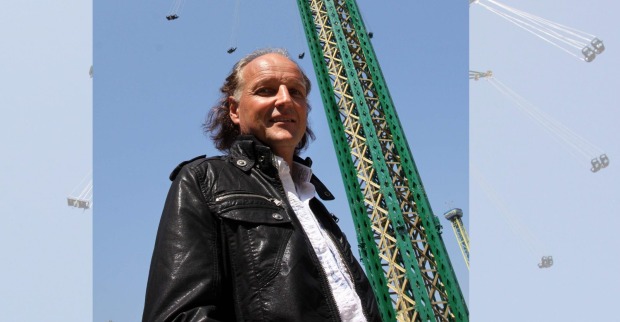 Das berühmte, über 100 Meter hohe Kettenkarussell Prater Turm ragt in den blauen Himmel über dem Wiener Prater, Walter Pondorfer steht davor