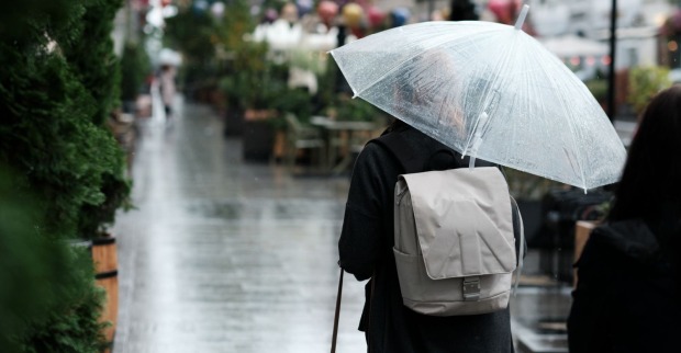 Verregnete Straße und Frau die Regenschirm hält