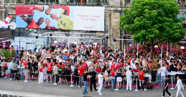 Menschenmenge beim Public Viewing am Donaukanal in Wien während eines Fußballspiels, viele Fans in rot-weiß gekleidet, Szene vor der Eskalation der Gewalt