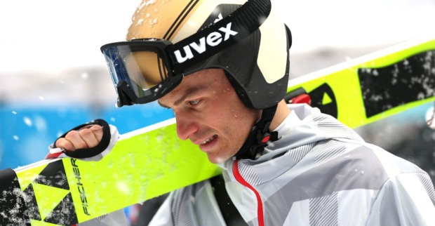 Johannes Lamparter mit Skiern auf der Schulter im Wettkampf, sichtbar angespannt nach dem Aus der Nordischen Kombination aus dem Olympia-Programm