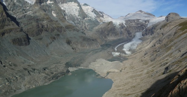 Ein schwindender Eisstrom am Fuße des Großglockners mit freiliegenden Felswänden und einem entstehenden Gletschersee