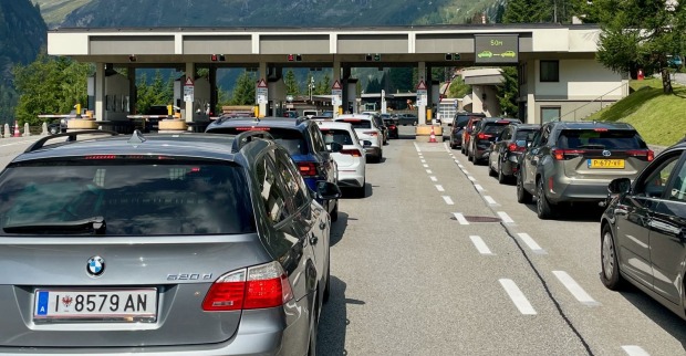 Eine lange Kolonne von Autos steht Stoßstange an Stoßstange im dichten Stau auf einer österreichischen Autobahn vor einer Bergkulisse
