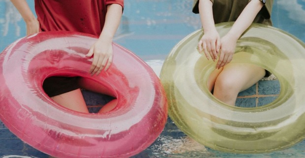 Wasserrutsche Wien: Zwei Personen sitzen mit aufblasbaren Schwimmringen am Wasser. Das Symbolbild steht für den Sommer-Spaß rund um die 75 Meter lange Wasserrutsche mitten in Wien.