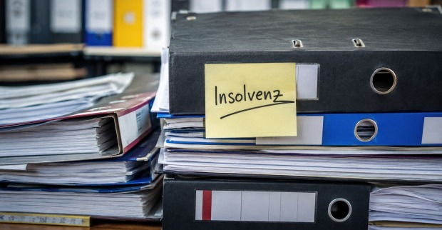 Büro mit Mappen und einem Post-It auf dem Insolvenz geschrieben steht