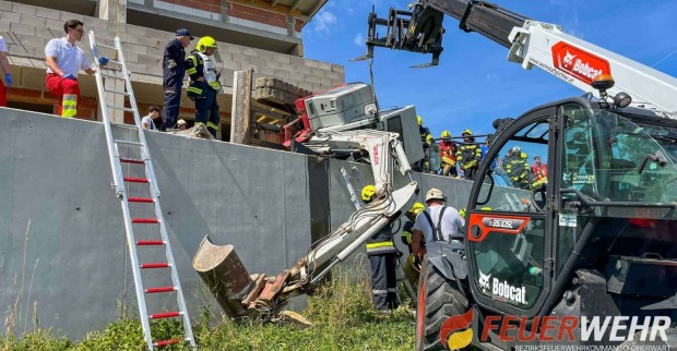Umgekippter Bagger bei Feuerwehreinsatz in Oberdorf im Burgenland mit Einsatzkräften und Teleskoplader.