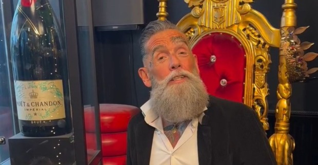 Roland „Crazy Cheese“ Ludomirska sitzt vor einem goldenen Thron und einer großen Champagnerflasche.