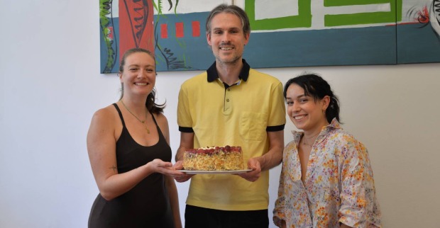 Cornelia Scheucher, Stefan Kohlmaier und Nina Dam, die in der Redaktion des Weekend Magazin Steiermark eine Österreichtorte des Café Sitzwohl in die Höhe halten