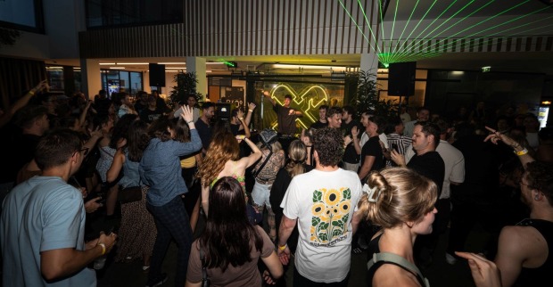 Mehrere Menschen tanzen vor einem DJ-Pult