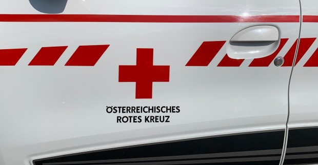 Farbiges Logo und Schriftzug auf deutsch mit dem Hinweis auf das Österreichische Rote Kreuz (ÖRK) auf der Seite des Krankenwagens.