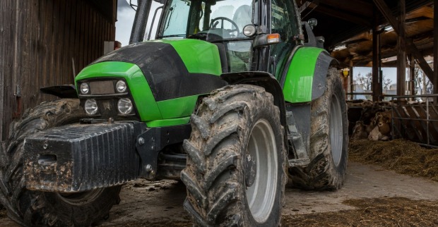 Grüner Traktor in einem Kuhstall als Symbolbild für den tödlichen Traktor-Unfall in Höchst in Vorarlberg.