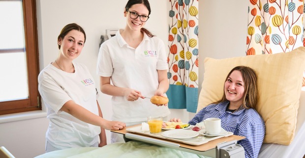 Junge weibliche Pflegekräfte am Bett einer Patientin | Credit: Caritas