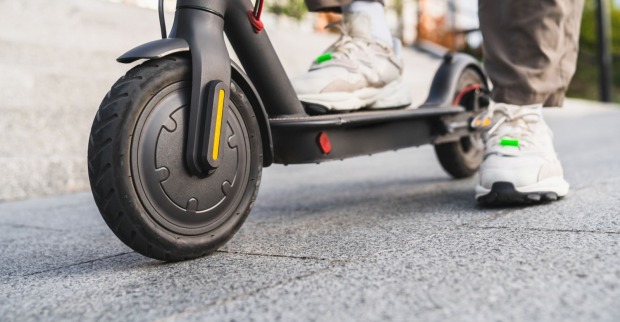 Mann steht auf einem E-Scooter