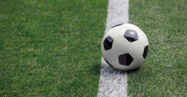 Ein Fußball liegt auf dem Spielfeld eines leeren Stadions